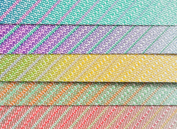 Extreme close up image of different coloured currency layered to create a rainbow effect